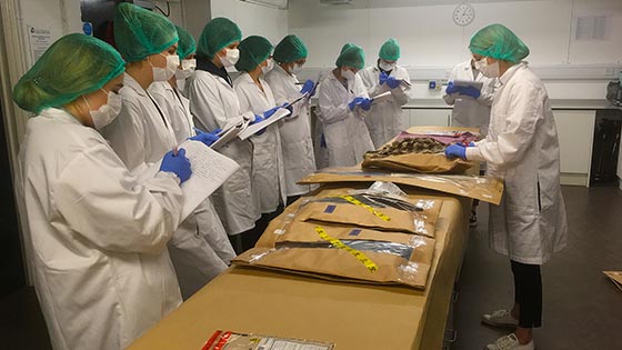 students and lecturer in white lab coats in forensics lab