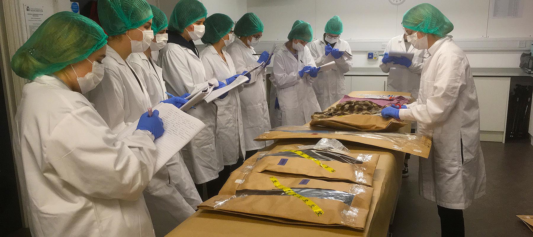 students and lecturer in white lab coats in forensics lab