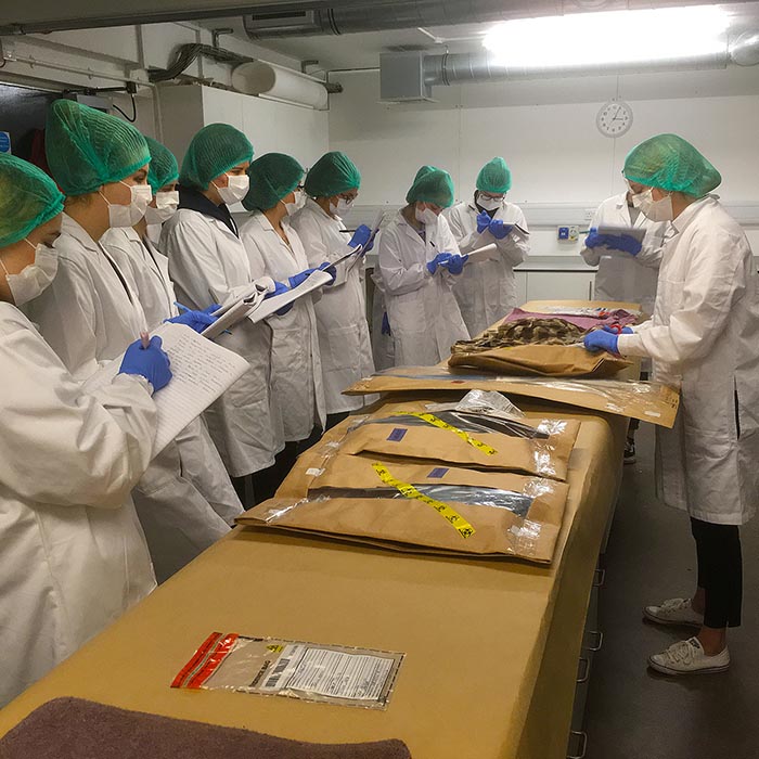 students and lecturer in white lab coats in forensics lab