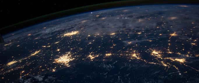 Zoomed out photo of earth in darkness with light from cities