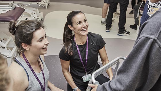 female lecturer kneeling on the floor looking up at student and smiling