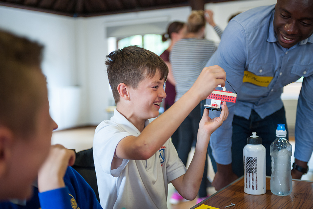 Child smiling while building Lego sculpture at school