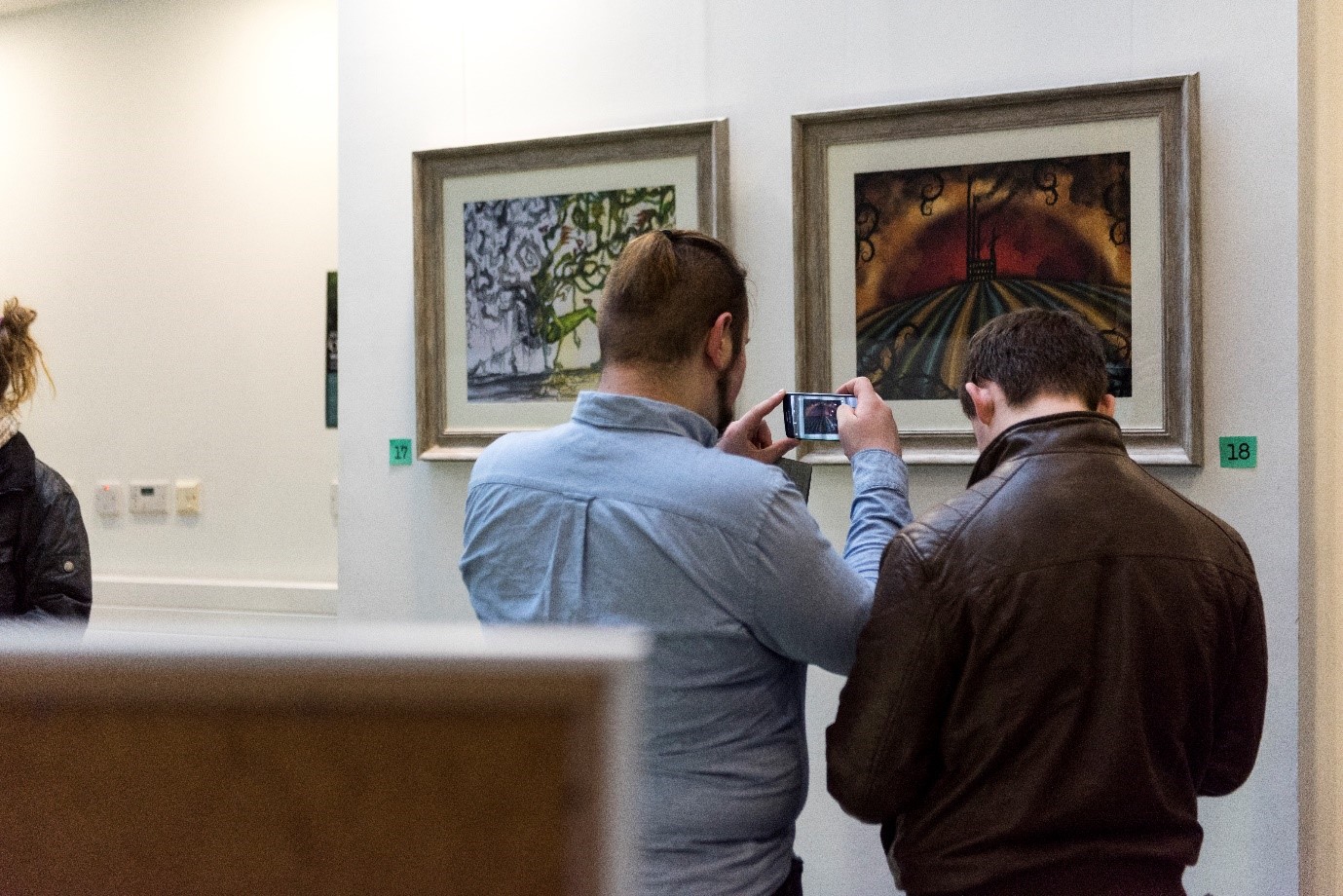 People viewing paintings at This changes everything exhibit