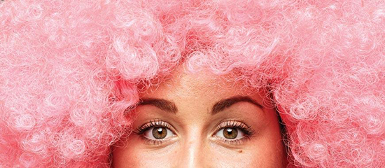 Eyes and forehead of woman in pink afro wig