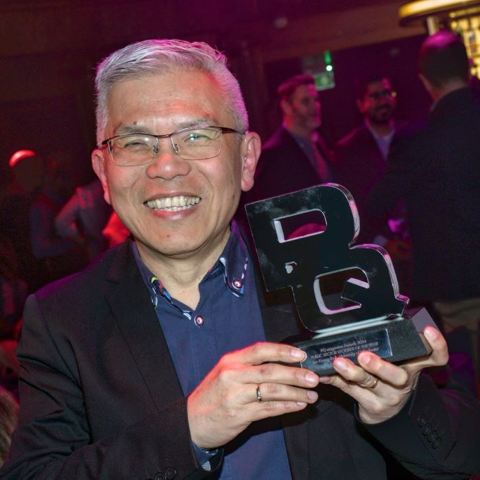 Man with trophy in shape of letters PQ