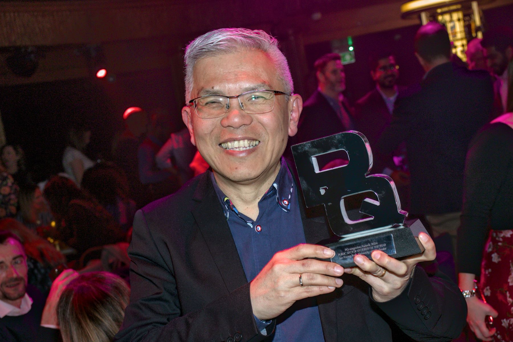 Man with trophy forming the letters 'PQ'