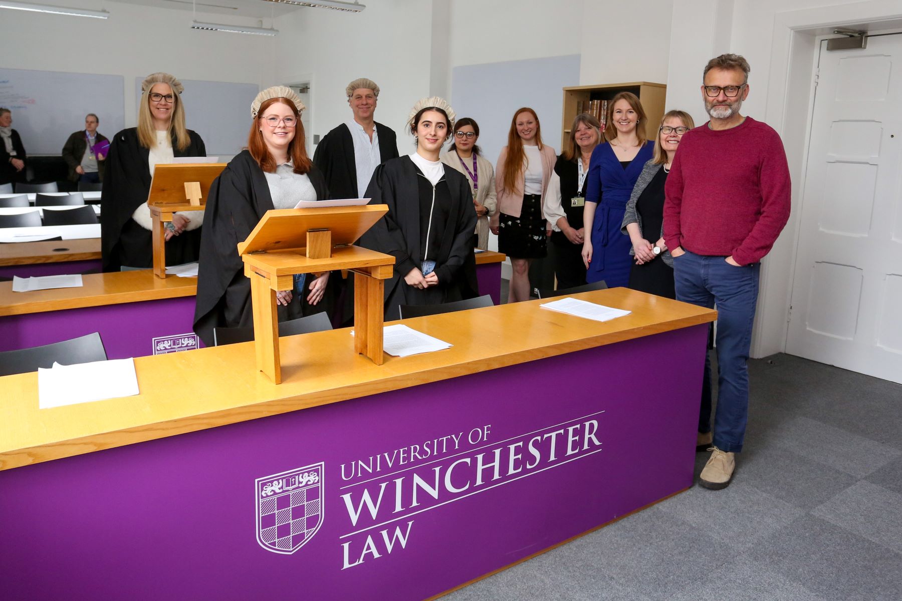 Law students in gowns behind purple desk saying  University of Winchester