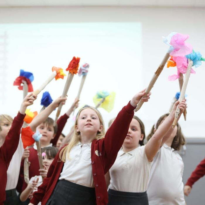 School children waving paper flowers