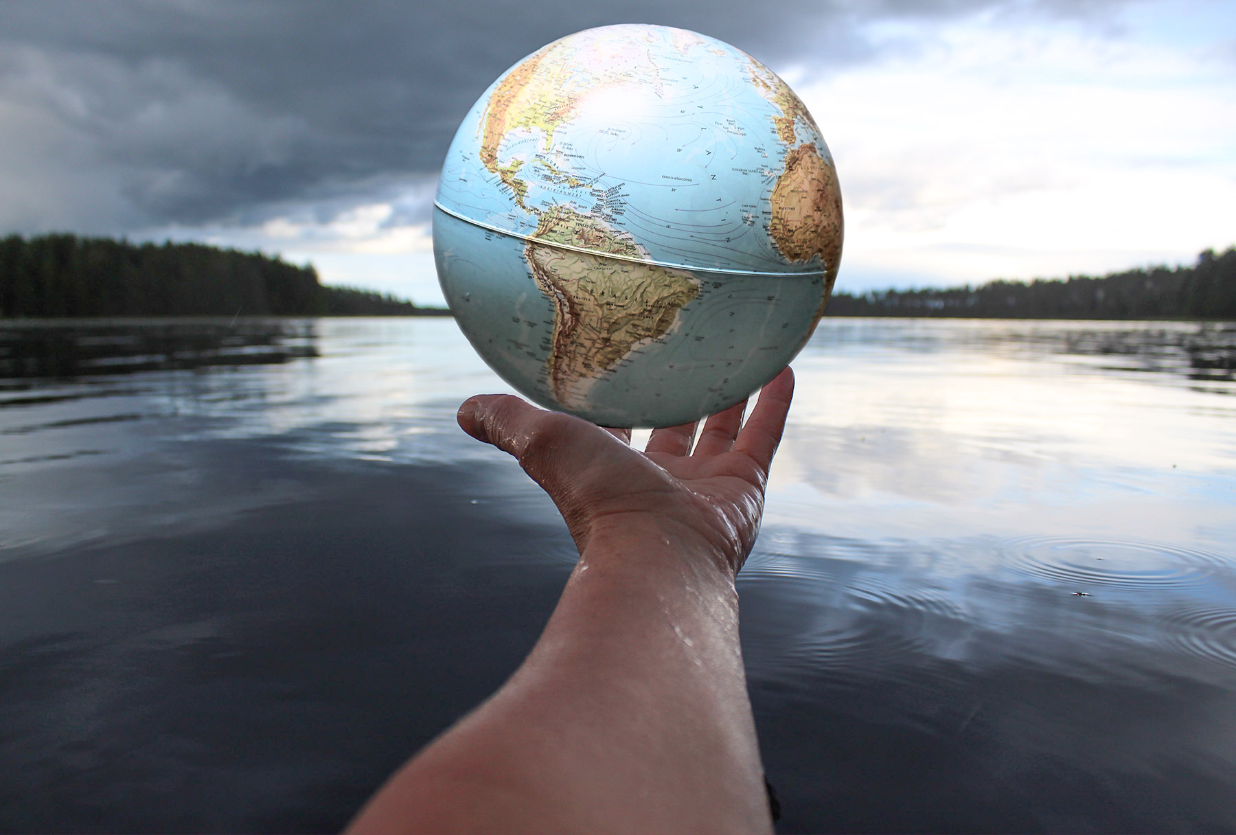 Someone holding a globe with a lake in the background