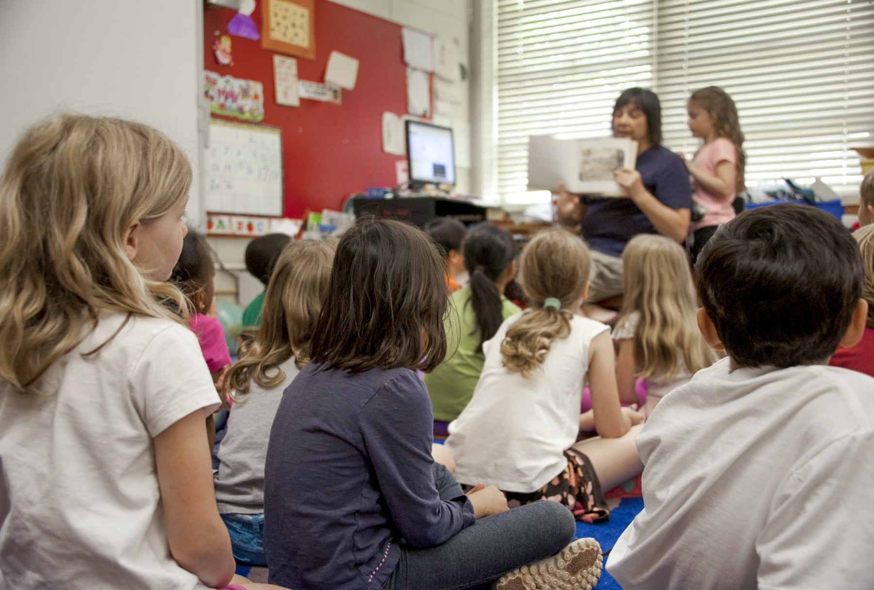 Teacher reading a book in front of a class of children