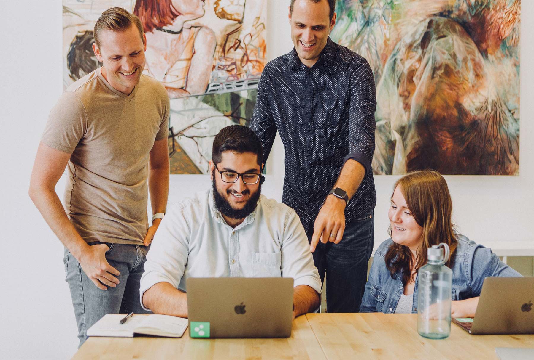 A group of adults around a laptop 