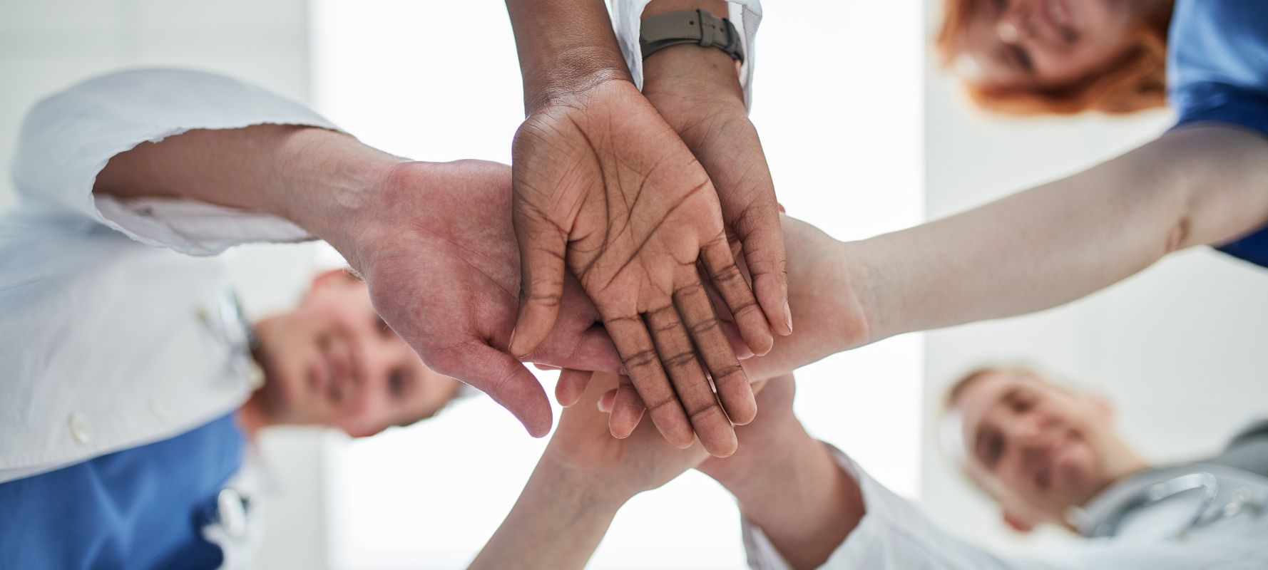 Individuals in circle with hands together in a pile