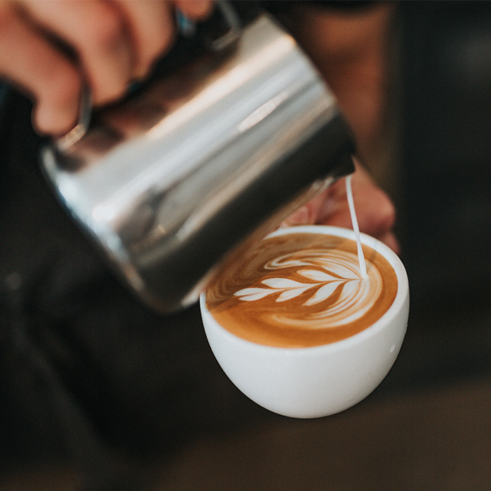 Milk being poured into a coffee mug in the shape of a leaf