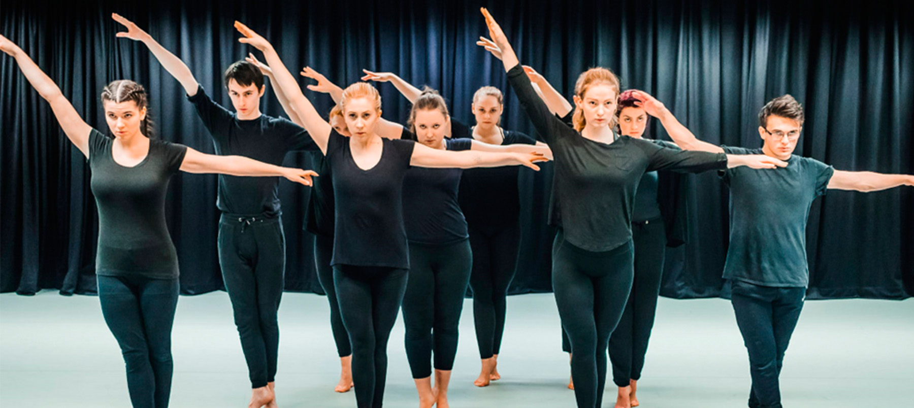 Group of dancers dressed in black standing in a line