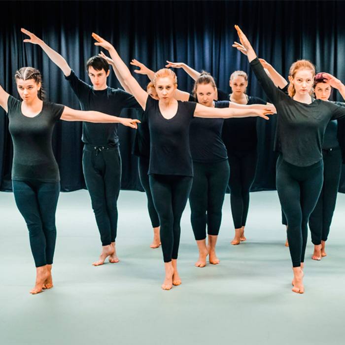 Group of dancers dressed in black standing in a line