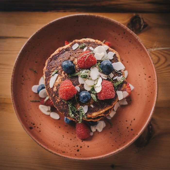 Pancakes and fruit in plates and bowls on a table