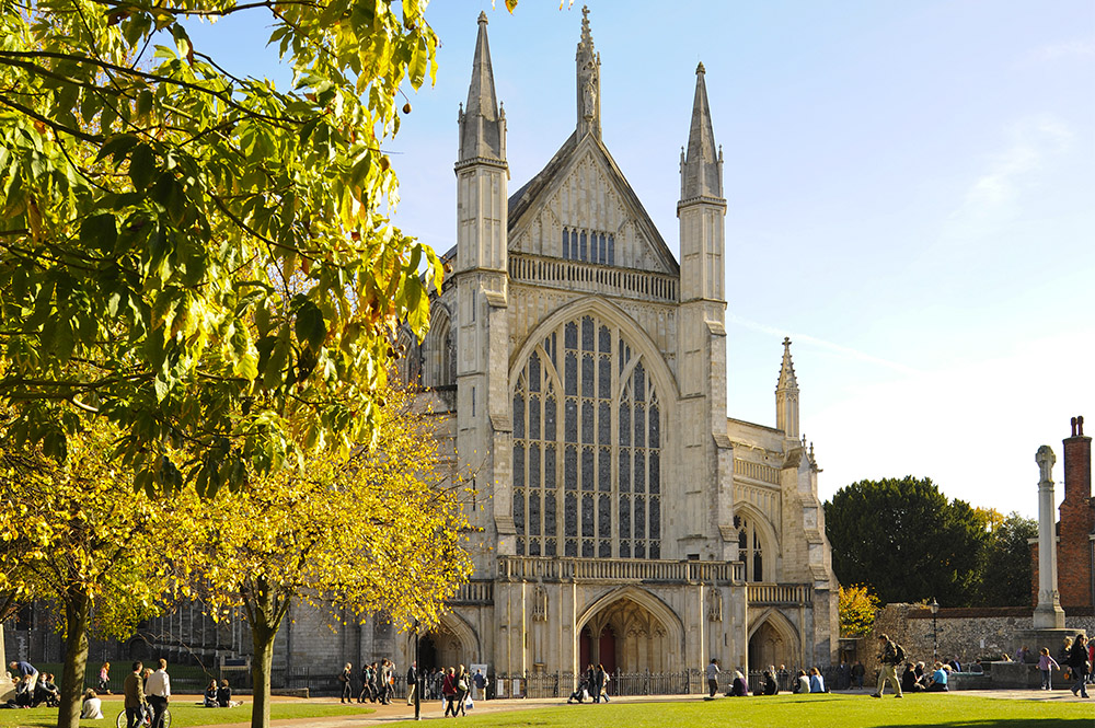 Cathedral grounds, with archways, blossom on trees and an window with flowers