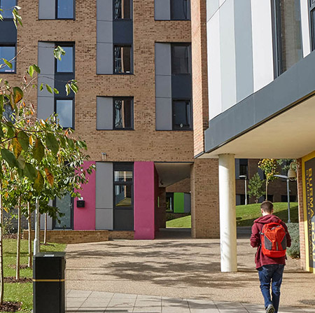 Exterior of block of flats with student walking by