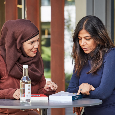 Student sitting with staff member at a table outside