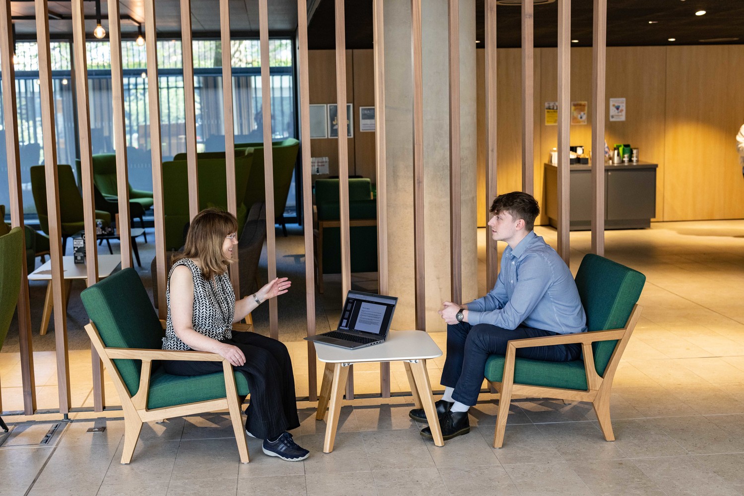 An alum and member of university staff chat in a cafe
