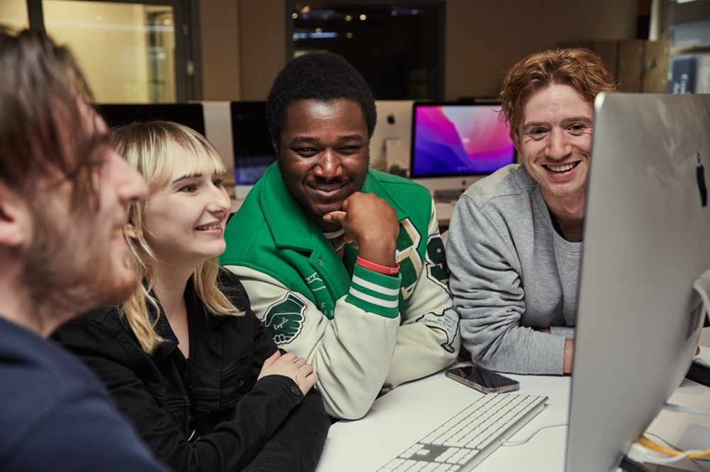 A group of happy students around a computer