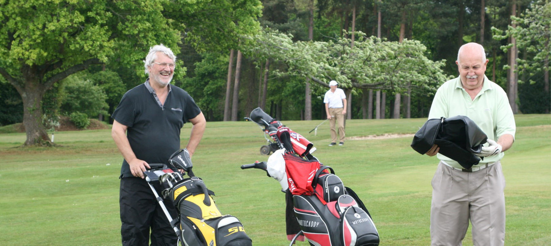 Alumni with golf bags stood on golf course