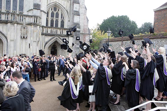 Students in graduation robes celebrating outside Winchester Cathedral