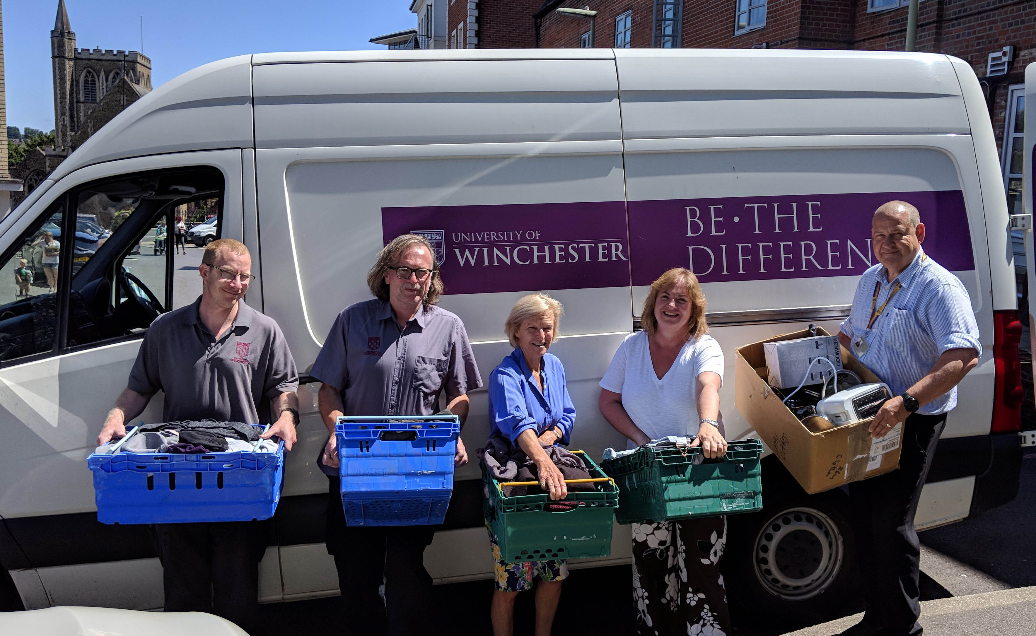 University porters and nightshelter volunteers holding donations by University delivery van