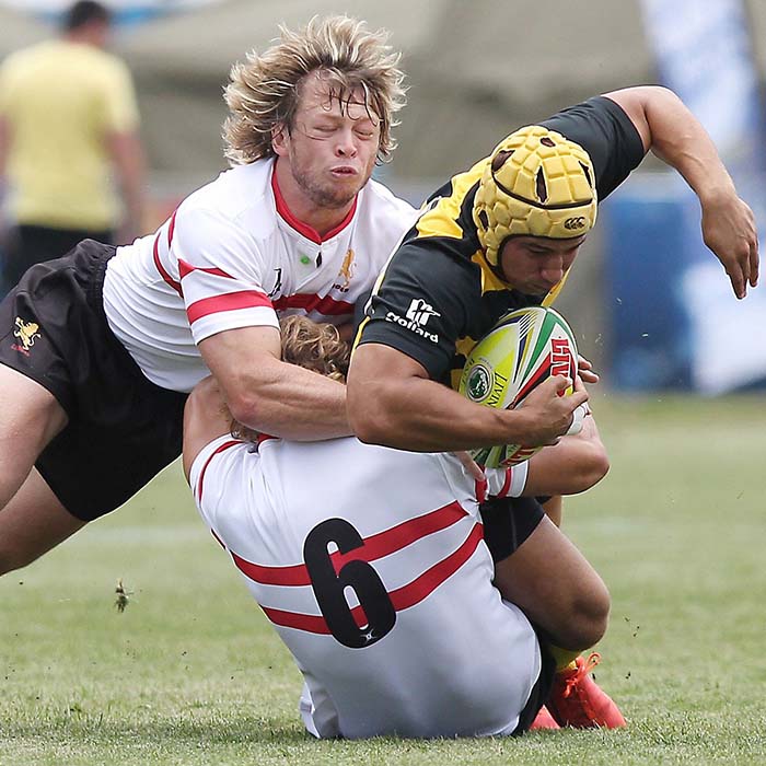 Three rugby players in a tackle