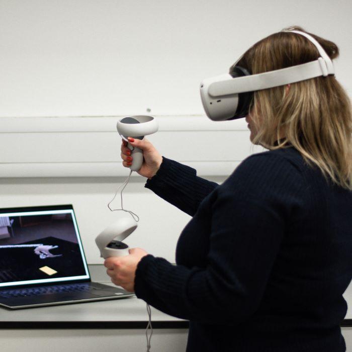 Girl with VR headset and handset in front of laptop VC