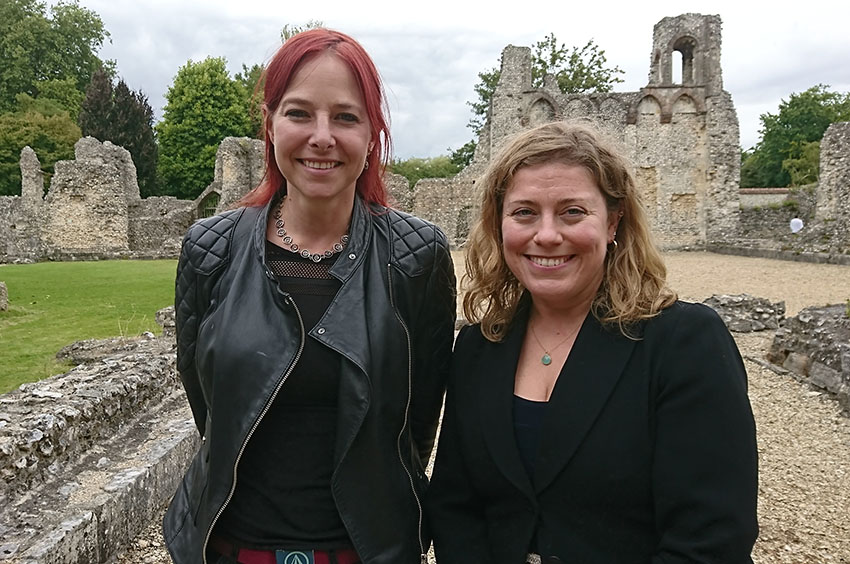 Two women smiling and standing side by side in ruins of Wolvesey Castle