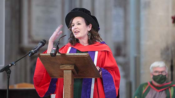 Elaine Cameron in graduation robes speaking at the lectern