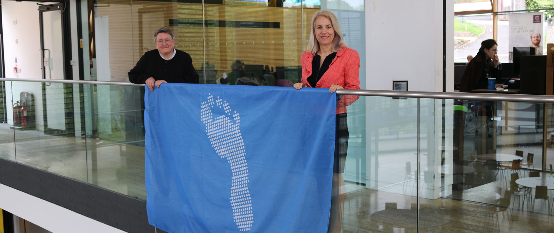 Joy Carter and Liz Stuart holding the blue footprint flag