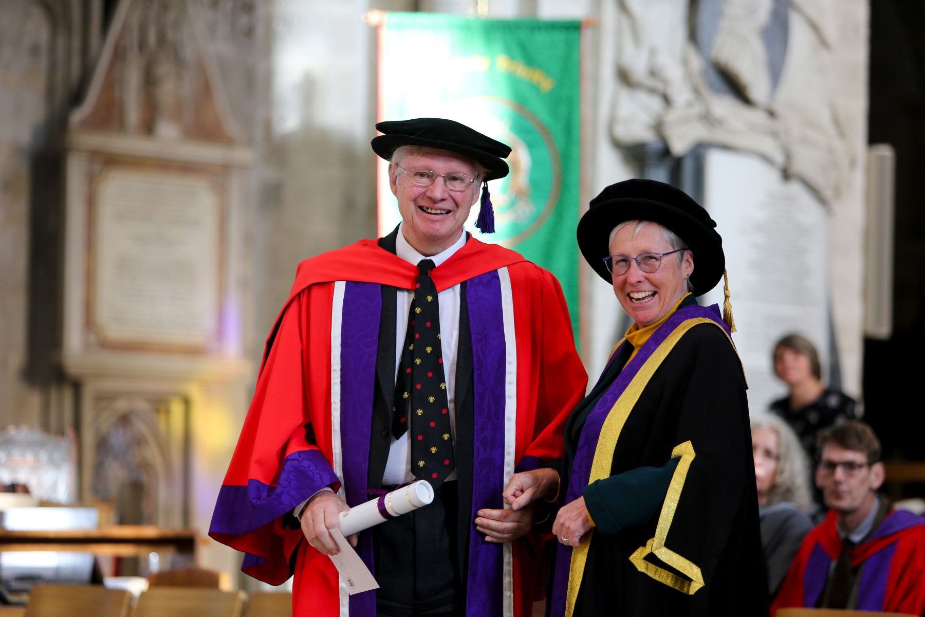 A man and woman in colourful academic robes