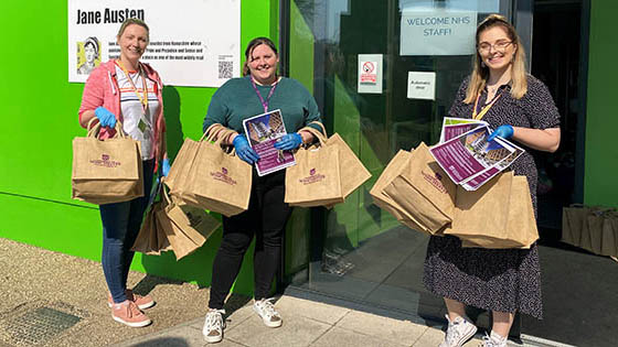 Three female staff with welcome bags standing outside halls of residence