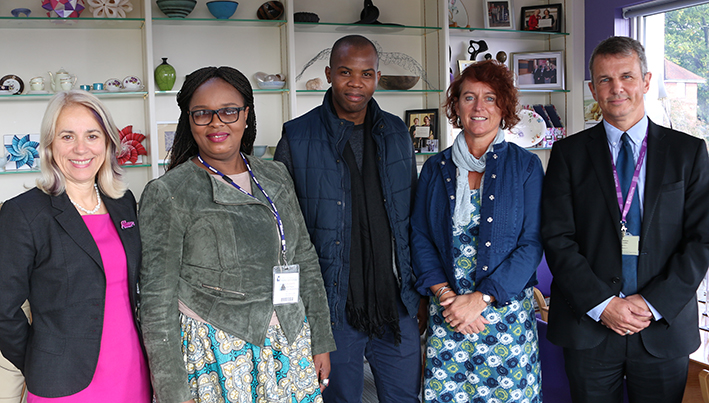 Group of five University and Mandela Museum members standing in front of a display bookcase