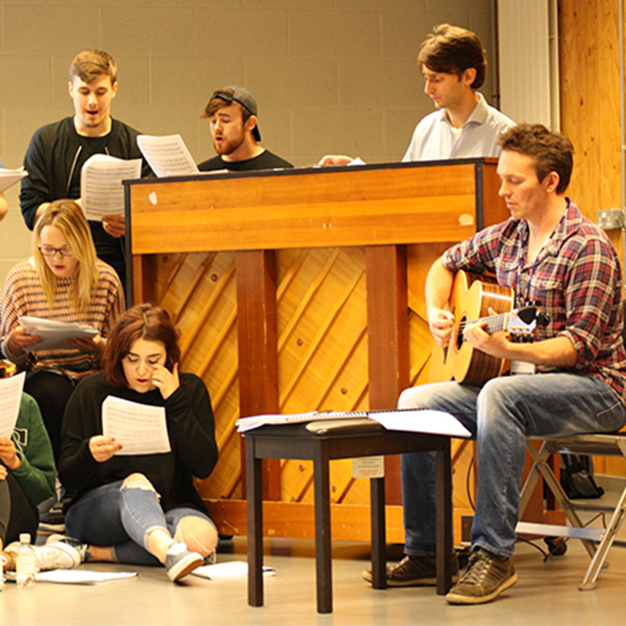 Group of people singing around a piano