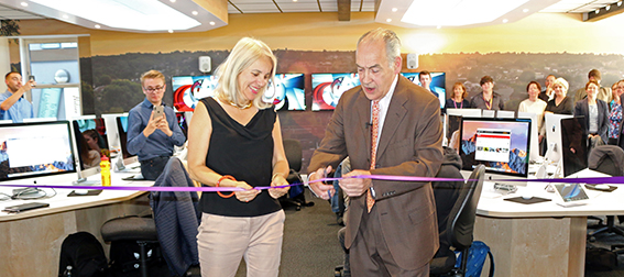 Man and woman cut ceremonial ribbon together in newsroom