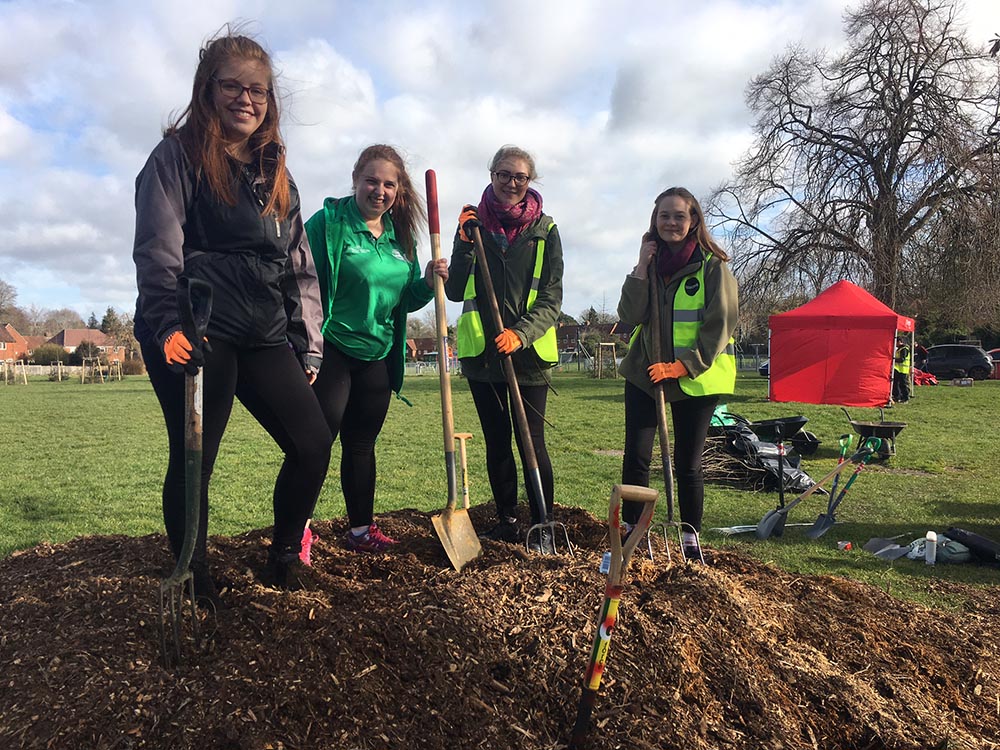 Four student volunteers with spades digging a garden