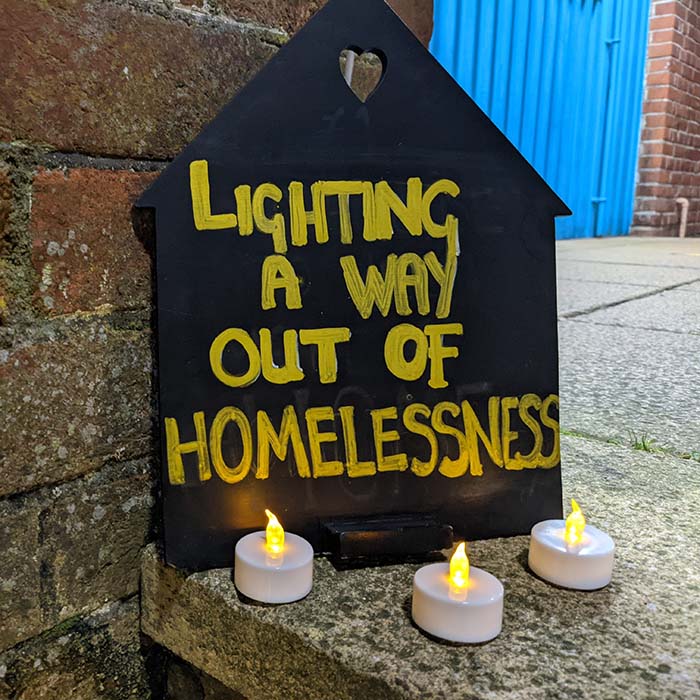 Lighting a way out of homelessness sign with candles