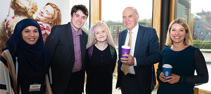 Vince Cable standing with one man and three women holding a branded reusable coffee cup