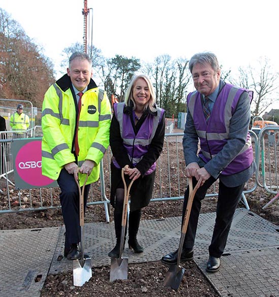 Three people in high vis jackets with spades digging a hole in the earth