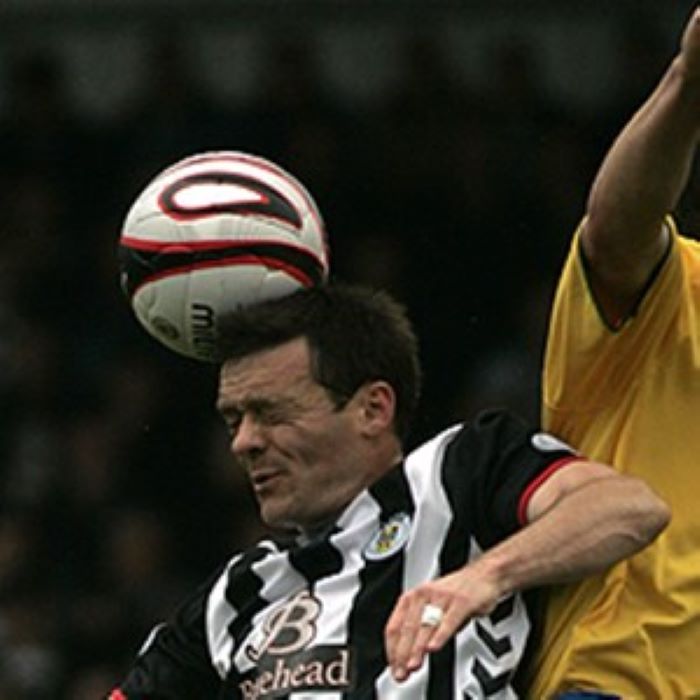 Football in black and white striped shirt heads the ball