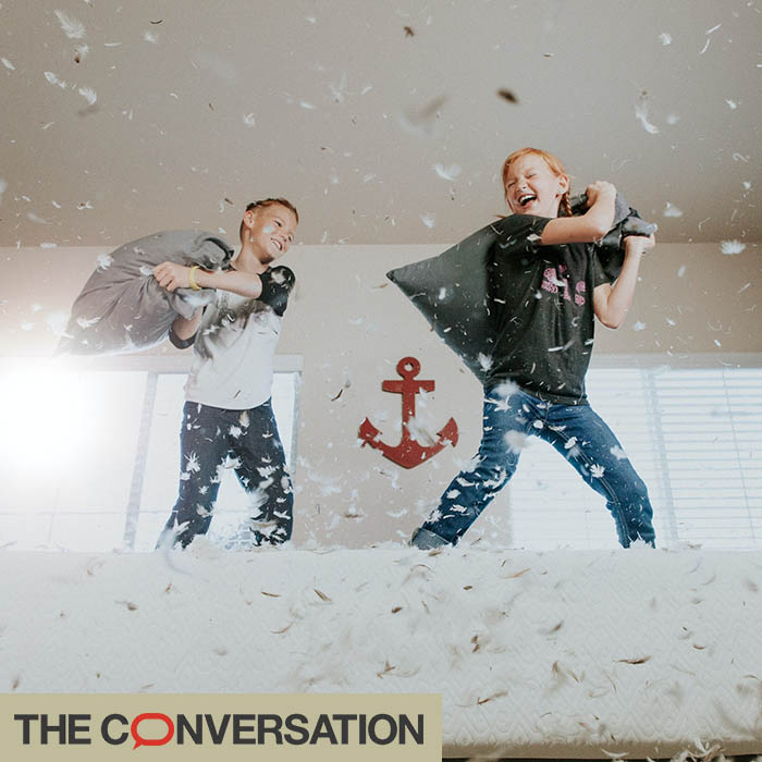 Two boys having a pillow fight