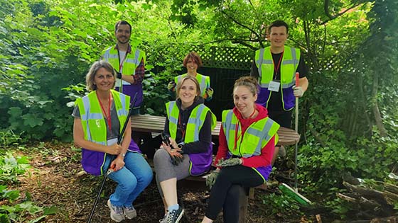 Six volunteers sitting on a bench in the woodland garden at Osborne School
