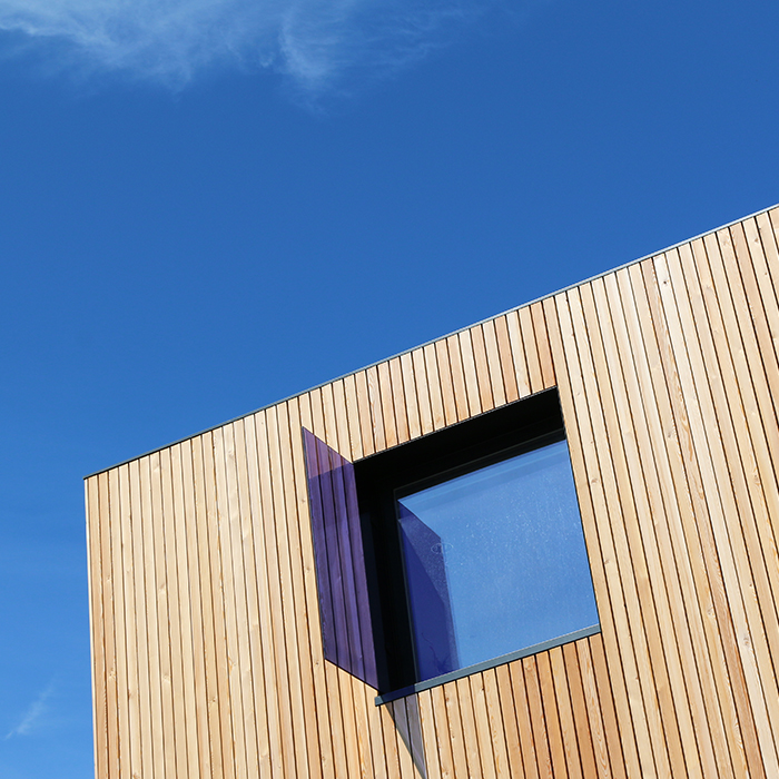 Top of timber clad contemporary building against a bright blue sky