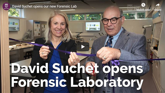 Still from video of Joy Carter with David Suchet cutting purple ribbon at new Forensic laboratory opening