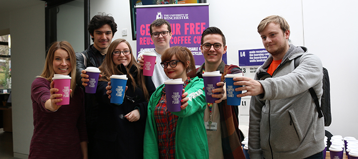 Students holding Gumdrop recycled, reusable coffee cups branded with the University logo