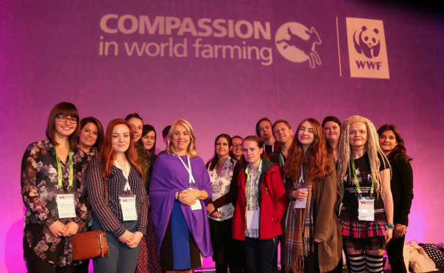 Extinction and Livestock conference attendees, including Vice Chancellor Joy Carter stand under 'WWF: Compassion in world farming' projection