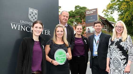 Six University representatives pictured with Green Tourism Award beside University sign